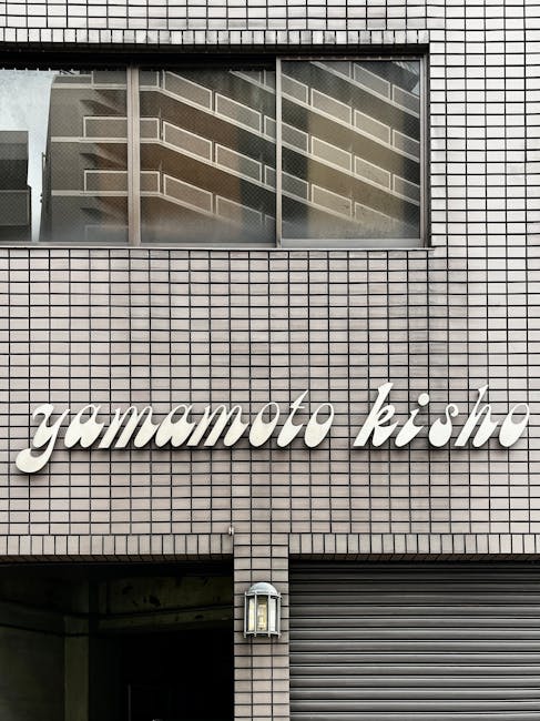 Front view of a building facade featuring 'Yamamoto Kisho' signage, showcasing urban architectural design.